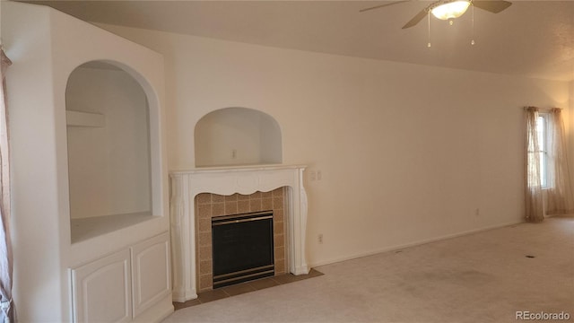 unfurnished living room with a tiled fireplace, light carpet, and ceiling fan