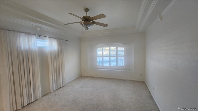 empty room with ceiling fan, ornamental molding, a raised ceiling, and light carpet