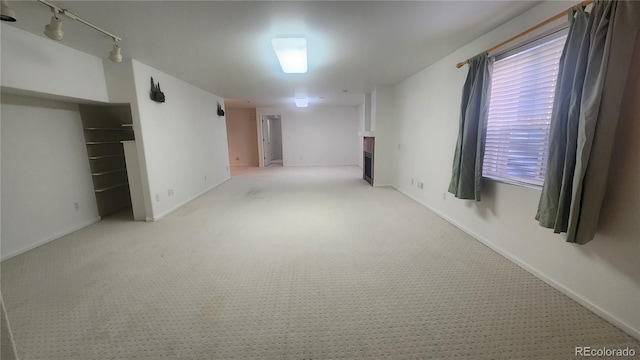 basement featuring light colored carpet and track lighting