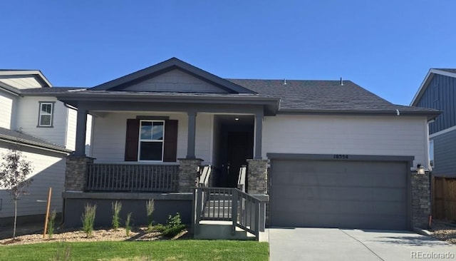 16554 W 93rd Way, Arvada, CO 80007 - view of front of home featuring a porch, a garage, driveway, and stone siding