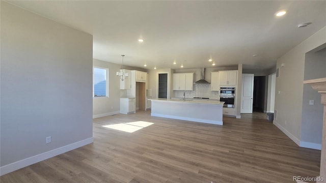 16554 W 93rd Way, Arvada, CO 80007 - kitchen featuring wall chimney exhaust hood, white cabinetry, double oven, recessed lighting, and backsplash