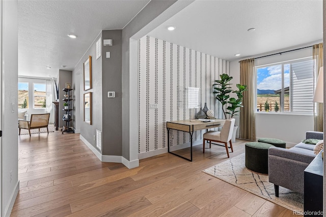 16554 W 93rd Way, Arvada, CO 80007 - living area featuring wallpapered walls, light wood-style flooring, an accent wall, a textured ceiling, and recessed lighting