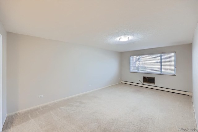 spare room featuring light colored carpet, a baseboard radiator, and a textured ceiling