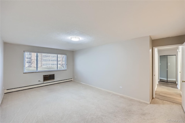 unfurnished room with light colored carpet, a textured ceiling, and baseboard heating