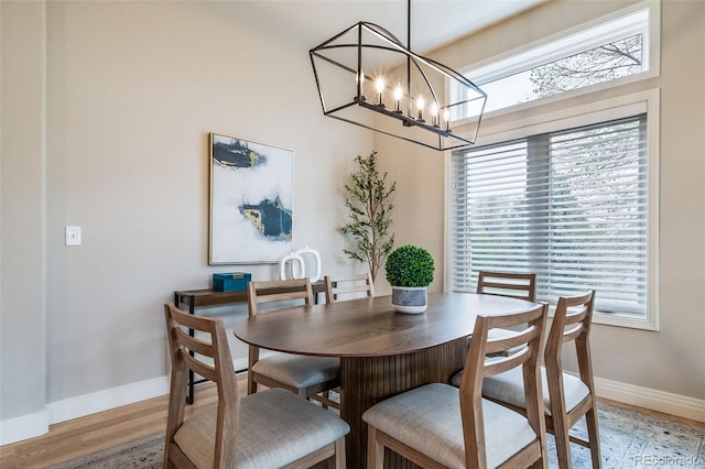 dining room with baseboards, a chandelier, and light wood-style flooring