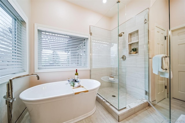 full bathroom featuring a stall shower, a freestanding bath, and tile patterned floors
