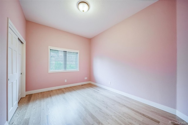 unfurnished bedroom with light wood-style floors, baseboards, and a closet