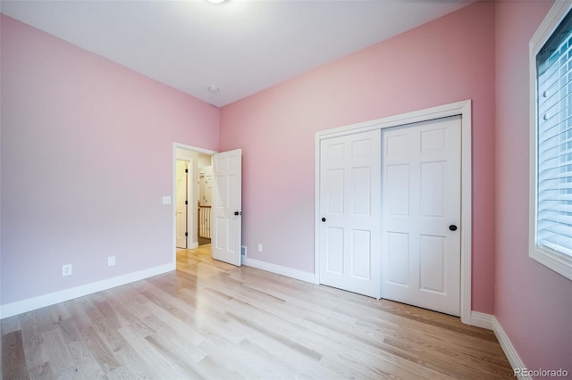 unfurnished bedroom with light wood finished floors, baseboards, and a closet