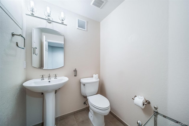 half bath featuring toilet, tile patterned flooring, a sink, and baseboards