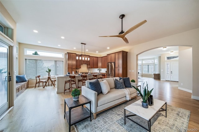 living area with arched walkways, light wood-style flooring, plenty of natural light, ceiling fan, and recessed lighting