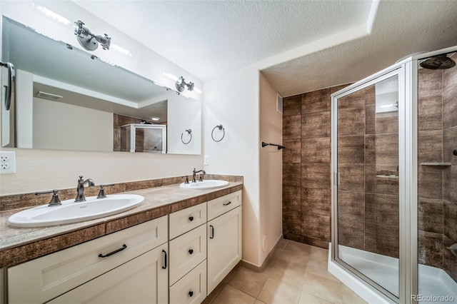 full bath featuring a shower stall, a textured ceiling, tile patterned flooring, and double vanity