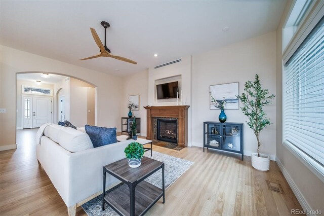 4532 Christensen Cir, Littleton, CO 80123 - living area featuring arched walkways, light wood-type flooring, a ceiling fan, a fireplace with flush hearth, and recessed lighting