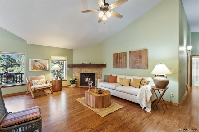 living area featuring wood finished floors, ceiling fan, a fireplace, and high vaulted ceiling