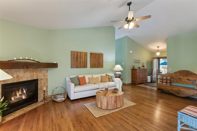 living room with wood finished floors, ceiling fan, a tiled fireplace, and high vaulted ceiling
