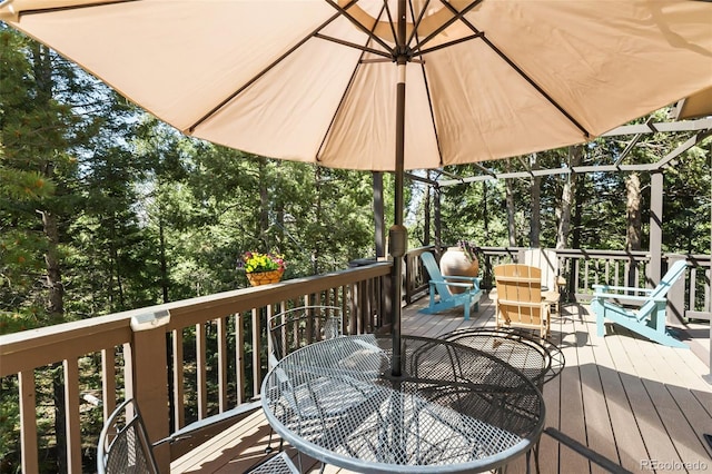 deck featuring outdoor dining space and view of wooded area