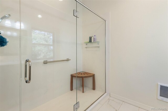 bathroom with a shower stall and marble look tiles