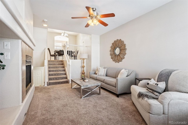 living room featuring a ceiling fan, stairs, and light carpet