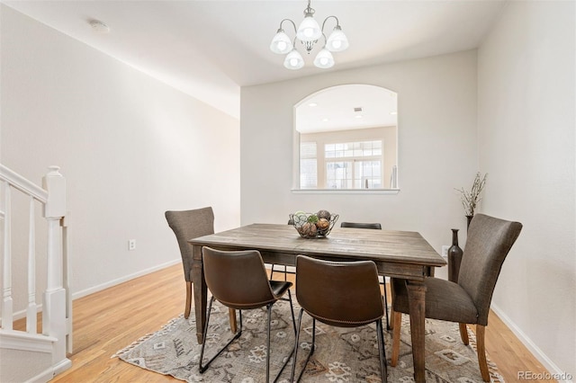 dining space with stairs, arched walkways, baseboards, and light wood-style floors