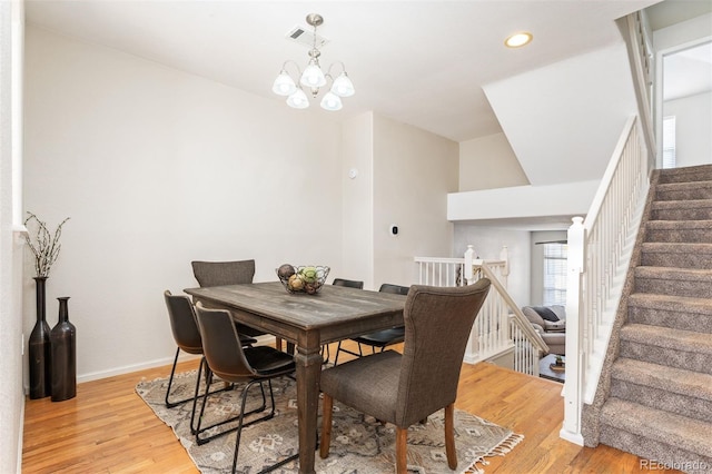 dining space featuring stairway, baseboards, light wood finished floors, and a chandelier