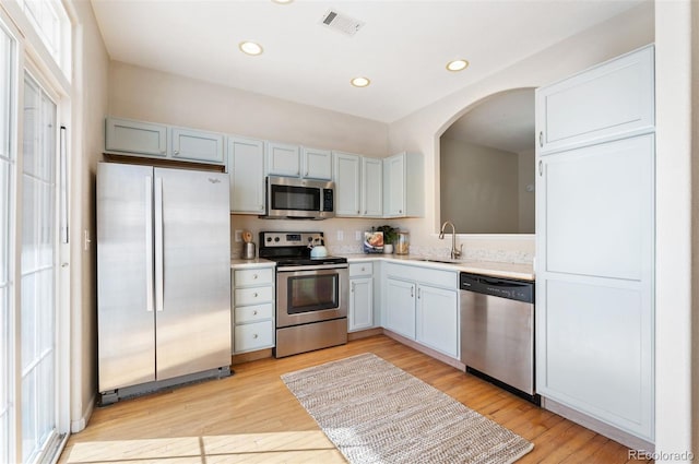 kitchen featuring visible vents, appliances with stainless steel finishes, arched walkways, a sink, and light countertops