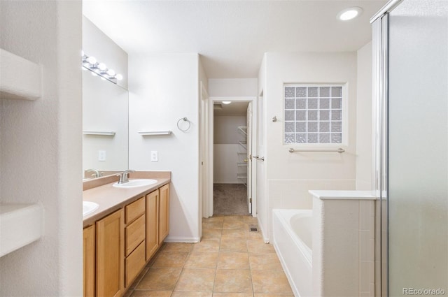 bathroom with double vanity, a stall shower, a sink, a bath, and a spacious closet