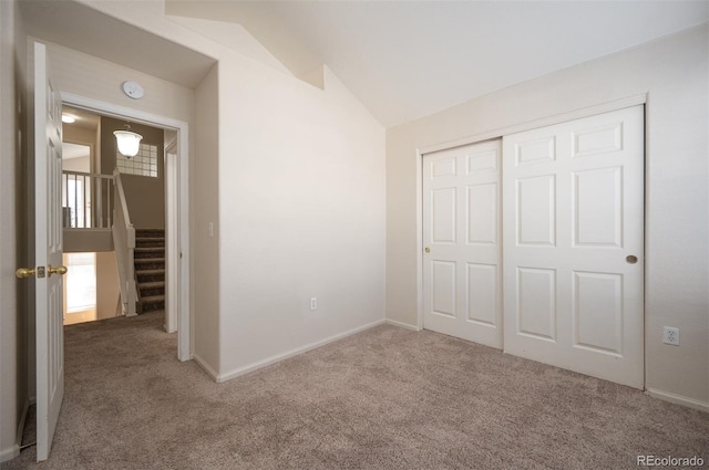 unfurnished bedroom with carpet flooring, baseboards, lofted ceiling, and a closet