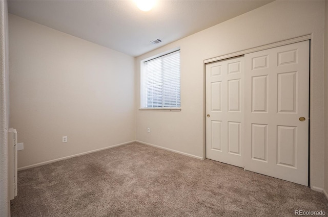 unfurnished bedroom with carpet floors, baseboards, visible vents, and a closet