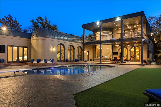 back house at dusk featuring a patio, a balcony, and ceiling fan