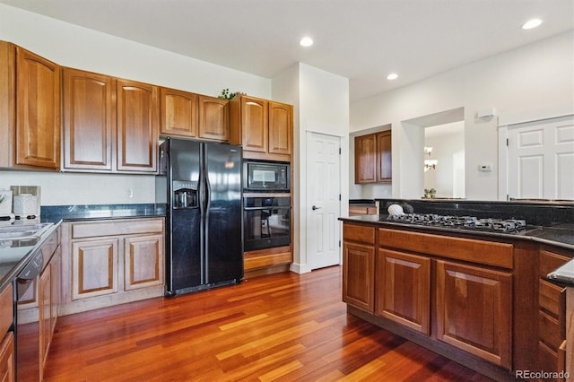5605 Killen Ave, Castle Rock, CO 80104 - kitchen with black appliances, dark wood finished floors, dark countertops, brown cabinetry, and recessed lighting
