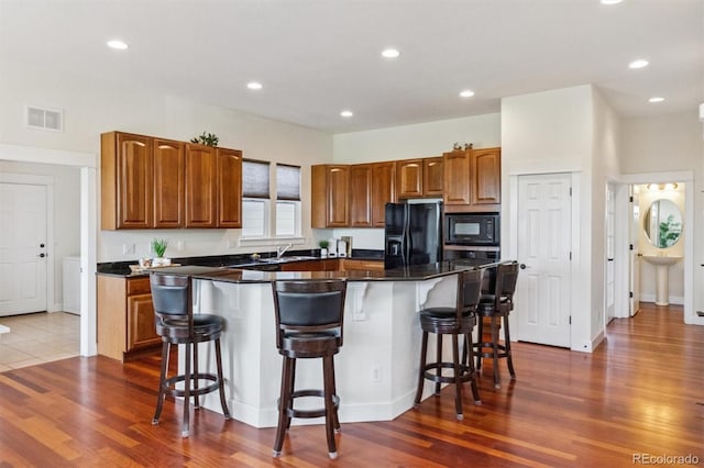 5605 Killen Ave, Castle Rock, CO 80104 - kitchen with black appliances, a center island, dark wood-style floors, a breakfast bar area, and brown cabinetry