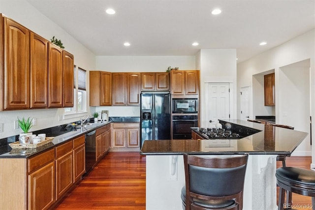 5605 Killen Ave, Castle Rock, CO 80104 - kitchen featuring black appliances, dark wood finished floors, a kitchen island, recessed lighting, and a kitchen breakfast bar