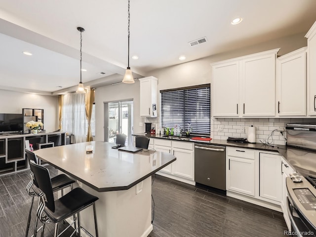 kitchen with stainless steel appliances, white cabinets, a kitchen bar, and decorative light fixtures