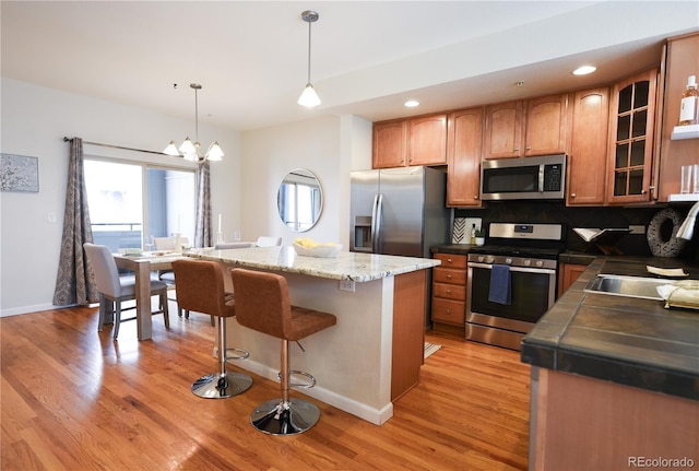 451 S Reed St, Lakewood, CO 80226 - kitchen featuring stainless steel appliances, light wood finished floors, a kitchen island, glass insert cabinets, and recessed lighting