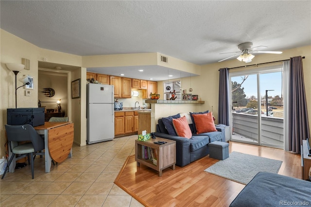 living area with light tile patterned floors, ceiling fan, a textured ceiling, recessed lighting, and visible vents