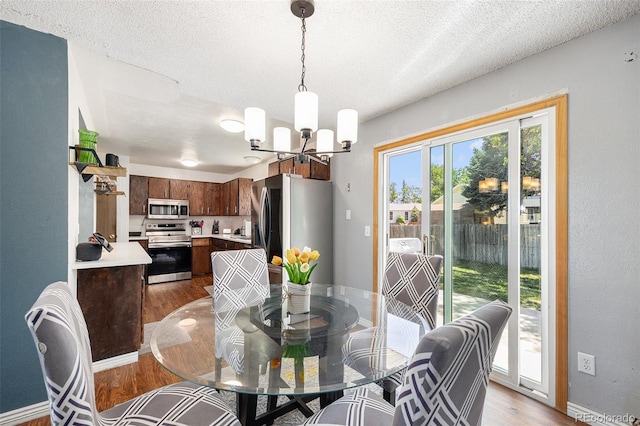 4844 E 110th Pl, Thornton, CO 80233 - dining room featuring a chandelier, wood finished floors, and a textured ceiling