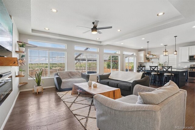 18079 E 108th Pl, Commerce City, CO 80022 - living area featuring wood finished floors, a tray ceiling, ceiling fan, recessed lighting, and baseboards