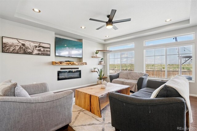 18079 E 108th Pl, Commerce City, CO 80022 - living area featuring wood finished floors, a tray ceiling, recessed lighting, ceiling fan, and baseboards
