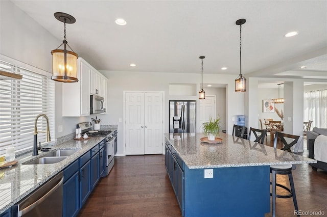 18079 E 108th Pl, Commerce City, CO 80022 - kitchen with stainless steel appliances, blue cabinetry, a sink, a kitchen breakfast bar, and white cabinets