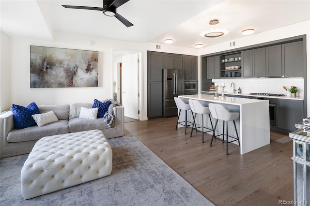 living room with ceiling fan, dark hardwood / wood-style floors, and sink