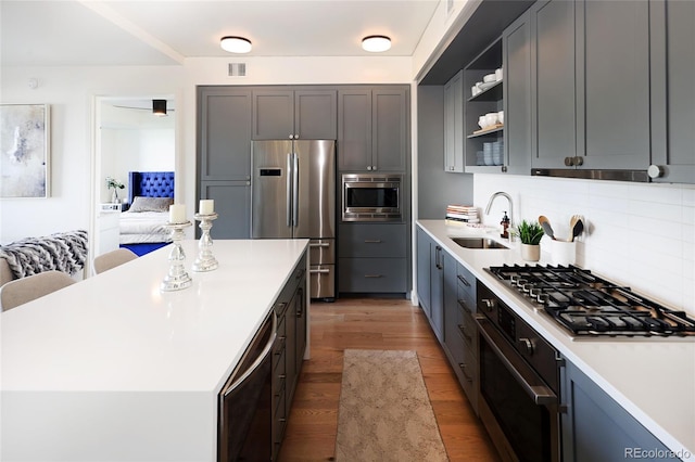 kitchen featuring sink, appliances with stainless steel finishes, hardwood / wood-style floors, a center island, and tasteful backsplash