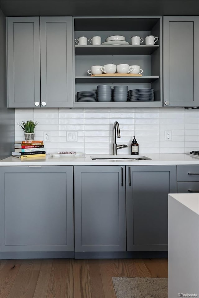 bar featuring gray cabinets, sink, and backsplash