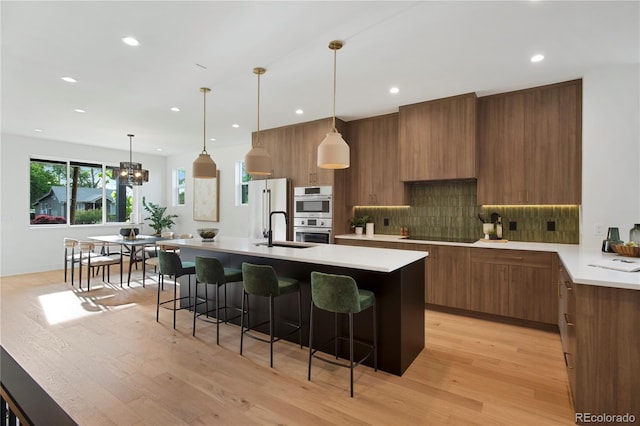 2450 S Cherokee St, Denver, CO 80223 - kitchen featuring modern cabinets, brown cabinets, light wood-type flooring, light countertops, and a sink