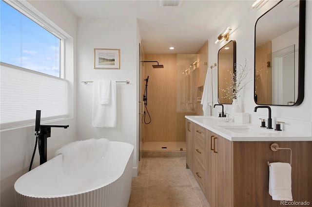 2450 S Cherokee St, Denver, CO 80223 - full bath featuring double vanity, a freestanding tub, a stall shower, tile patterned flooring, and recessed lighting