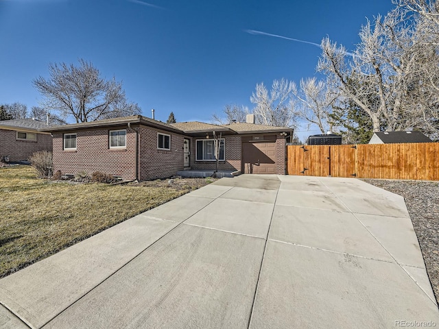 ranch-style home with fence, concrete driveway, a front yard, a garage, and brick siding