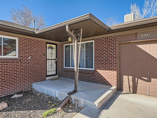 view of exterior entry featuring brick siding and a garage