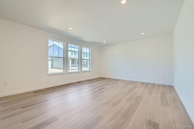 empty room featuring light wood-style flooring, recessed lighting, and baseboards