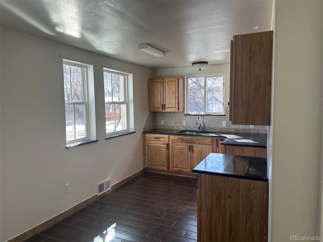 kitchen featuring dark wood-type flooring, dark countertops, visible vents, and backsplash