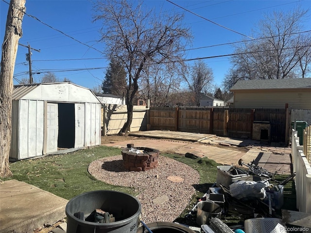 view of yard featuring an outbuilding, a storage shed, an outdoor fire pit, a patio area, and a fenced backyard