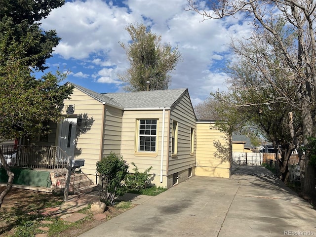 view of property exterior featuring roof with shingles and fence