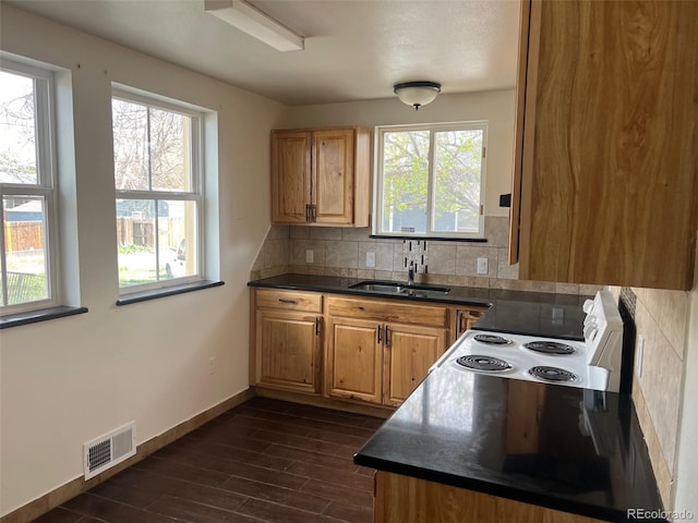 kitchen with white electric range oven, dark countertops, visible vents, and a wealth of natural light